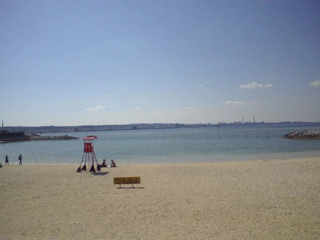 アメリカンビレッジがあり、休日はフリーマーケットで賑わう国際色豊かな町。一方、米軍基地に隣接し、昼間でも軍用機の轟音が鳴り響き、驚くこともある。ここはビーチだが遊泳禁止。遠くに宜野湾の街が見える。