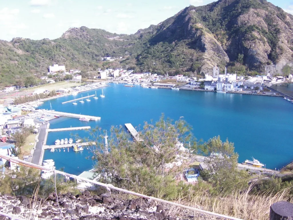 小笠原・父島の二見港の漁港部分。鮮やかな青い海と停泊する船、背後の山々を切り取る。