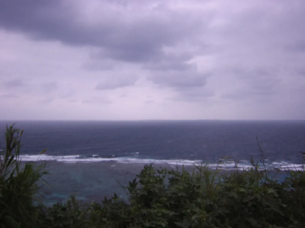 西海岸付近にて。崖を挟んで波打ち際が見える。この日はしけており、波の音が道路まで聞こえてきた。