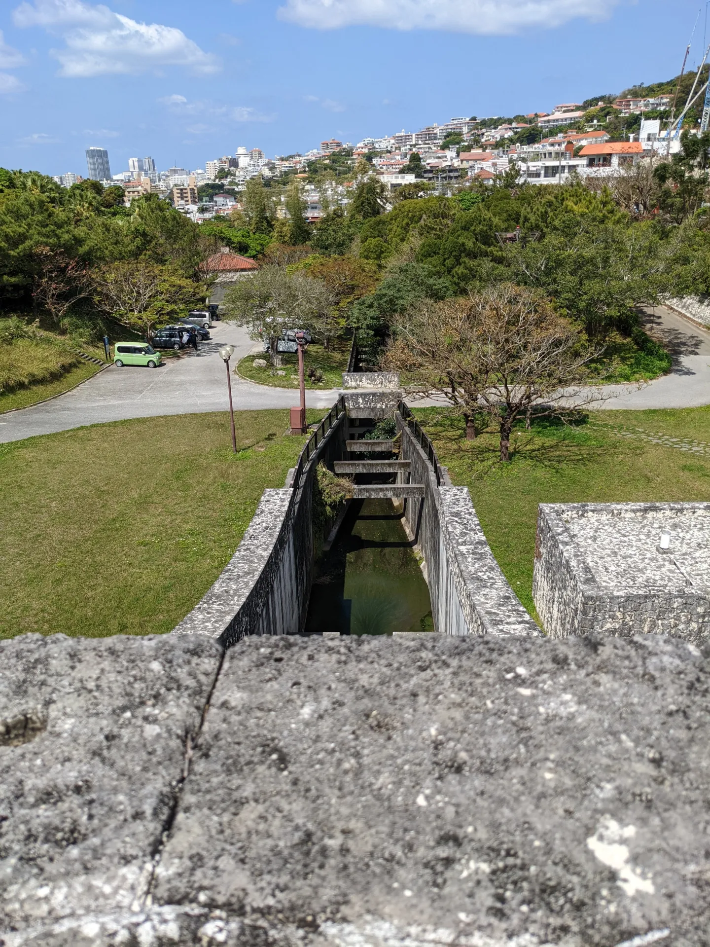 金城ダムの上から見下ろす公園と那覇の街並み