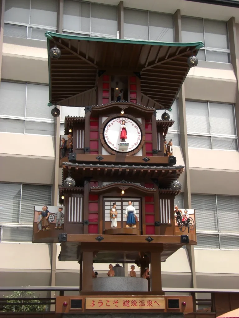 道後温泉駅前の広場にからくり時計が置いてある。毎正時になると、時計が伸び、中の人形が出てきて踊りだす。からくりが終わると松山の観光案内の放送が始まる。正時前になるとカメラやビデオに収めようとする観光客が集まってきていた。