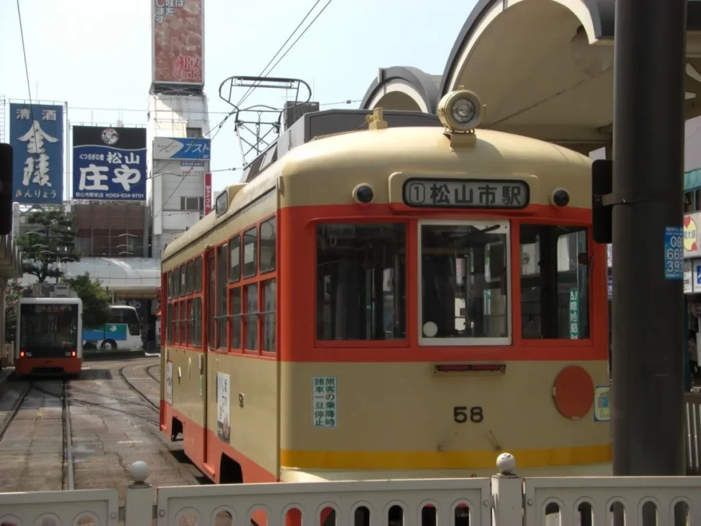 松山市駅の新旧車両松山の足は伊予鉄道が便利。市内は路面電車になっていてすぐ乗れる。道後温泉への直通電車や、市内環状線など、系統が多く使いやすい。車両は古く、2010年当時は、昭和20年代のものもあったが、新型車両への入れ替えが完了している。写真は松山市駅で出発を待つ路面電車。右が古い車両、左が新型車両。