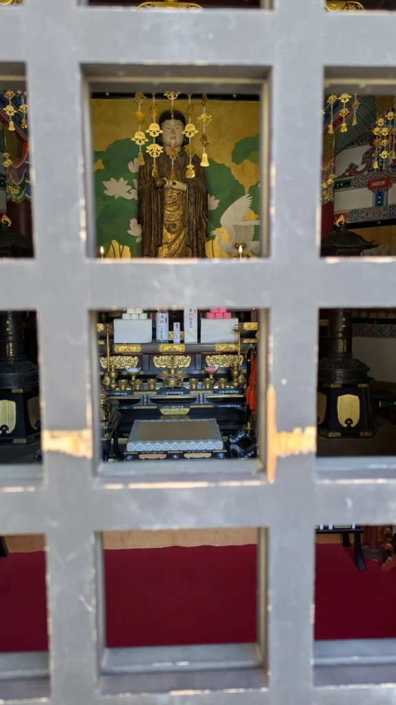 堂内に静かに安置された像。格子越しに手を合わせ、祈りを捧げる。