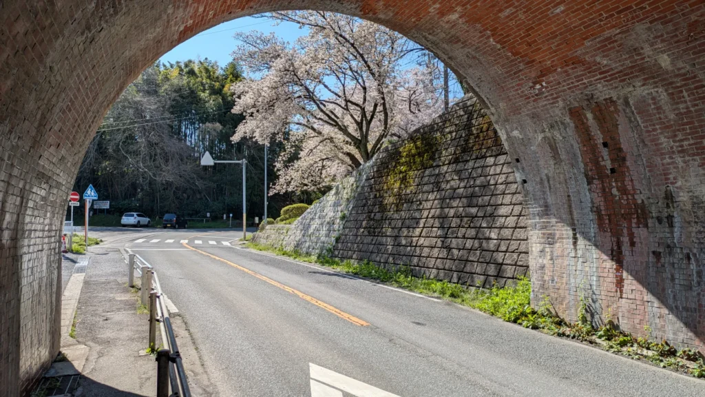 レンガのアーチ越しに覗く桜。暗いトンネルを抜けると春の色彩が広がる。